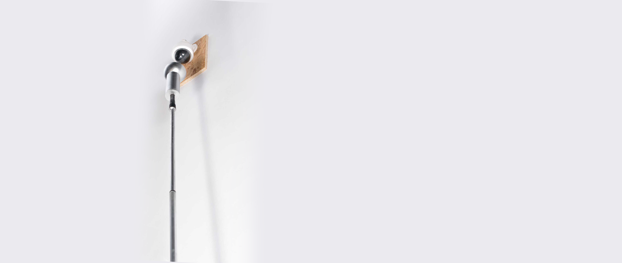 Een surveillance camera aan de muur, met een lange stok met bakje eronder gericht
